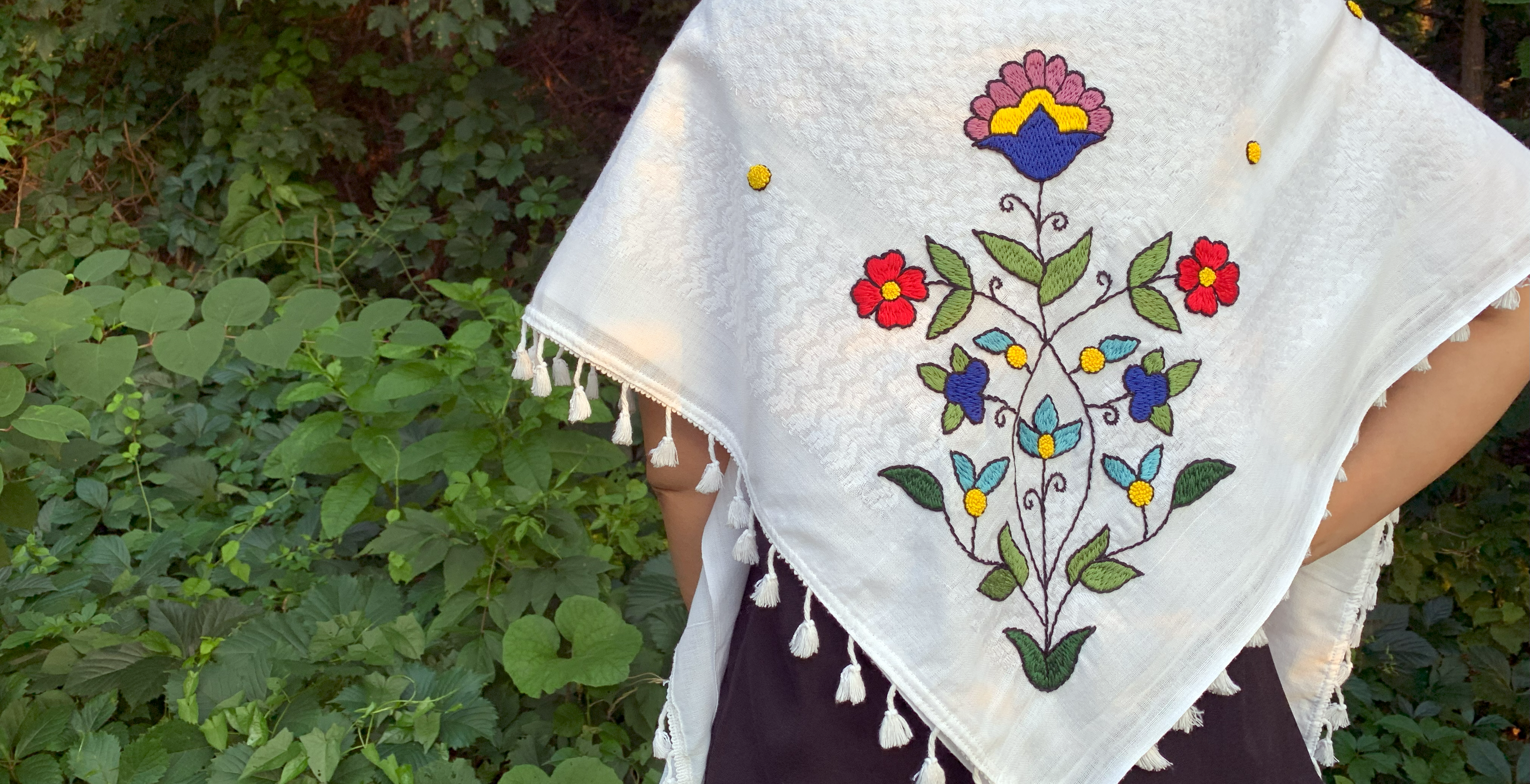Hand embroidered colorful floral design on a white shawl.